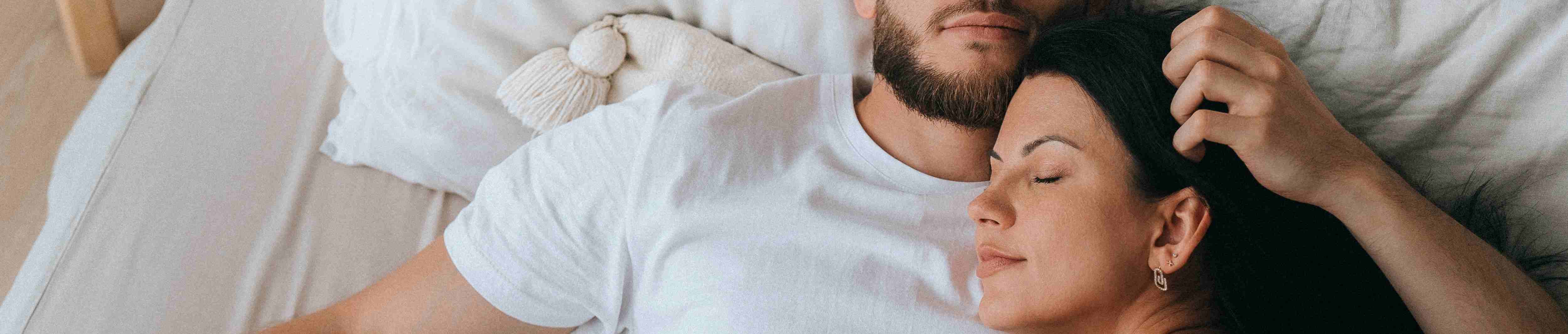 junges Paar kuschelt im gemeinsamen Bett